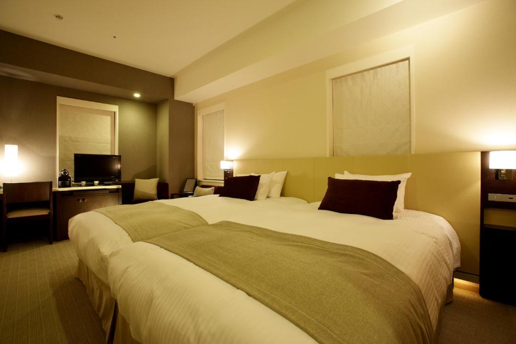 神户KOKO HOTEL Kobe Sannomiya的酒店客房设有一张大床和一台电视。