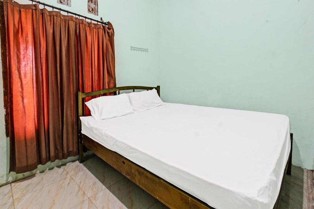 普拉亚SPOT ON 91771 Homestay Bang Haji的红色窗帘的房间的一张床位