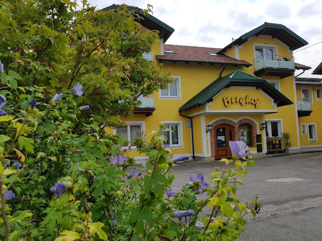 Obernberg am InnPension Baumgartner-Berghof的一座黄色的建筑,前面有紫色的花