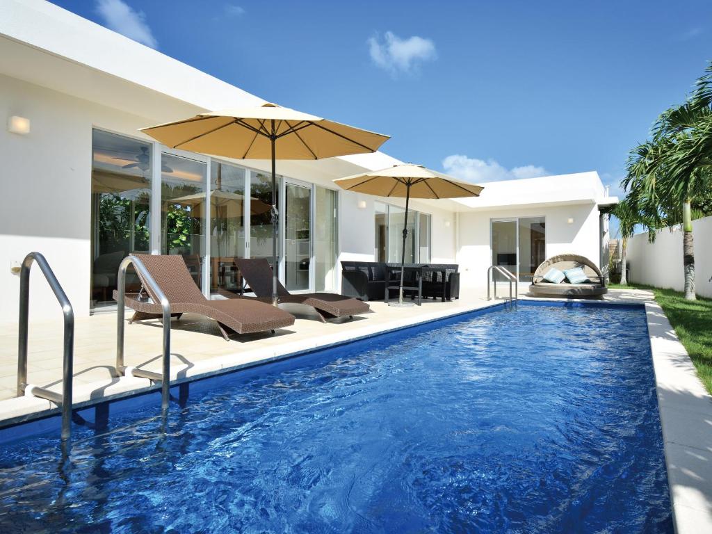 今归仁村Pool Villa Imadomari by Coldio Premium的房屋旁的游泳池配有椅子和遮阳伞