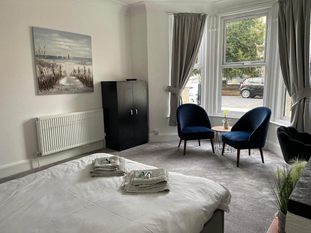 伊斯特布恩Impeccable 2-Bed Apartment in Eastbourne的一间卧室配有一张床、两把椅子和一张桌子