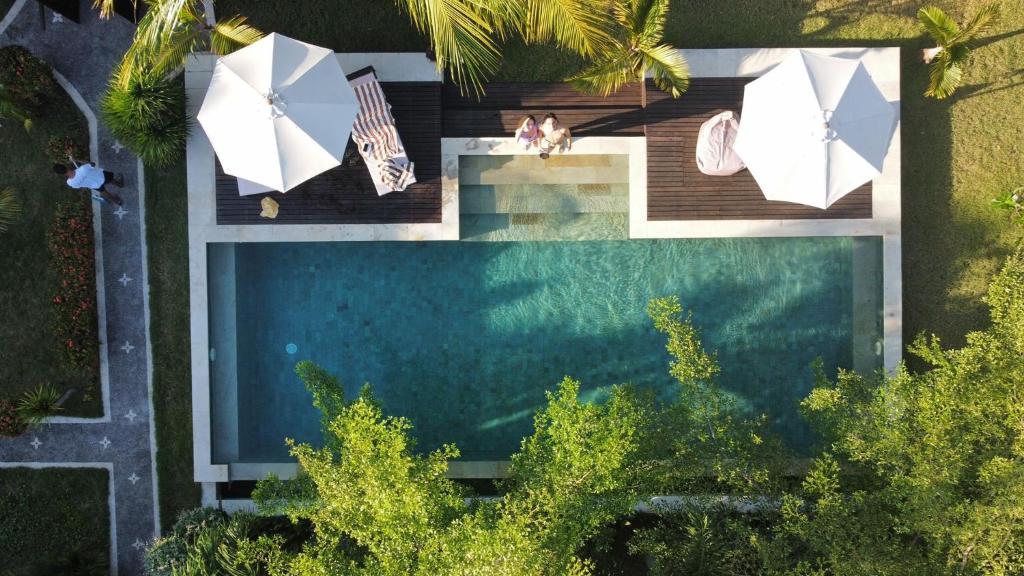 吉利阿尔Kaien Villas Gili Air的享有带遮阳伞的游泳池的顶部景致