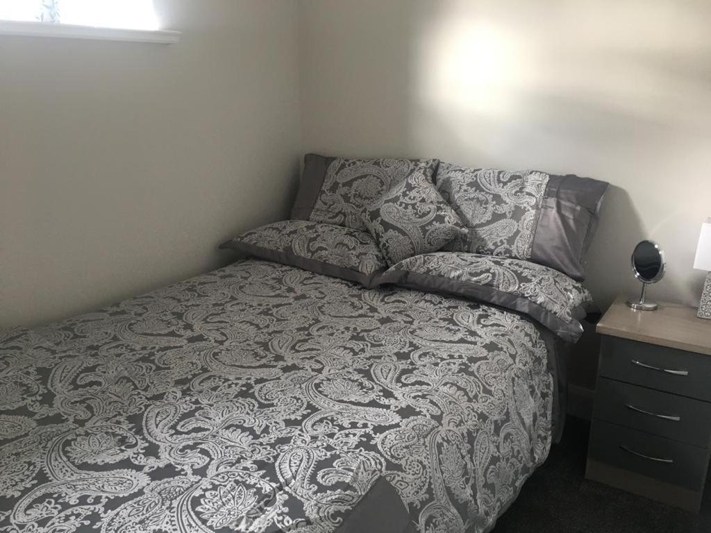阿马Dympna's City Centre apartment, Armagh的一间卧室配有一张带灰色毯子和枕头的床