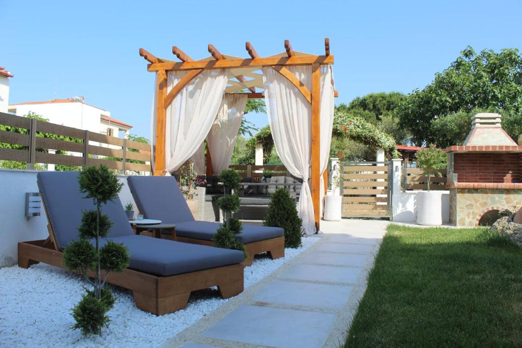 尼基季Azure Bliss Suites的一个带两把椅子的花园和一个木制凉亭