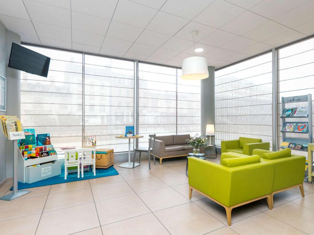 南希南锡中心阿德吉奥阿克瑟斯公寓式酒店的一间设有绿色沙发和桌子的等候室