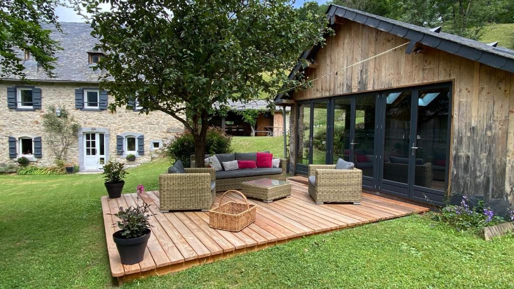 Arrens-MarsousLe Domaine de Castille - maison pyrénéenne de charme - spa de nage的庭院内一个带沙发和椅子的木制甲板