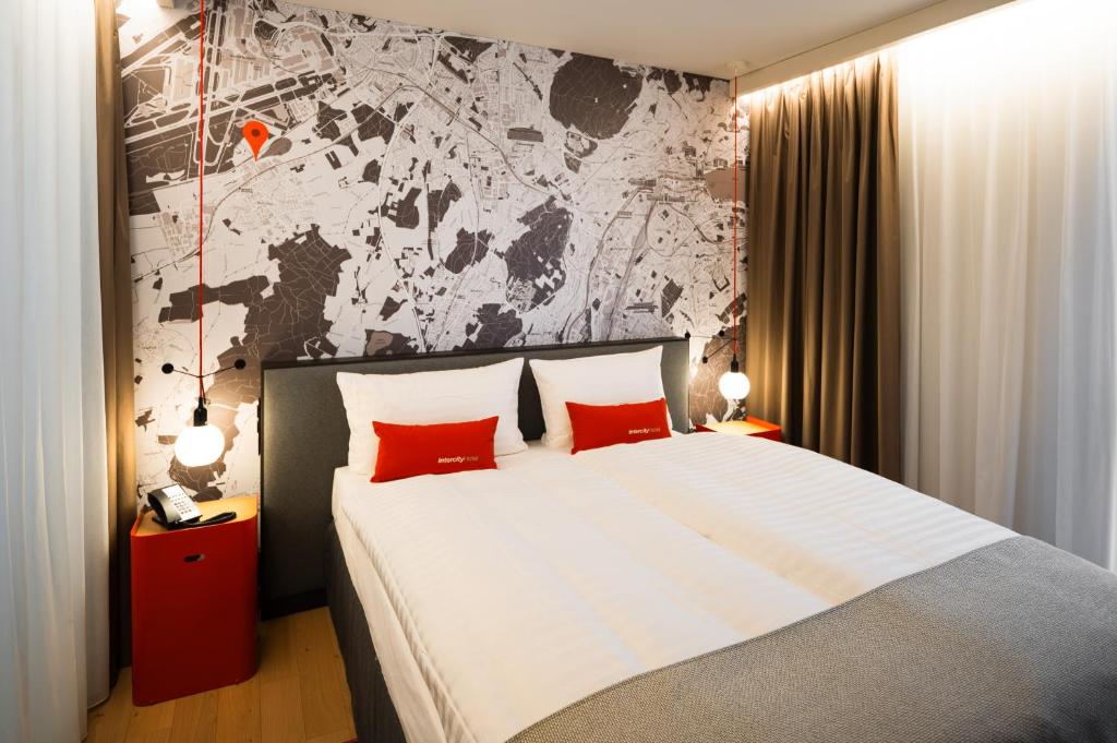 日内瓦IntercityHotel Geneva的一间卧室配有一张大床和两个红色枕头