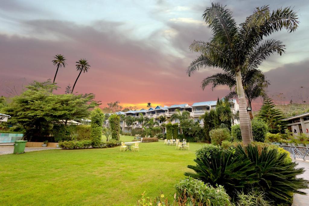 卜山Hummingbird Resort的度假村内拥有桌子和棕榈树的公园