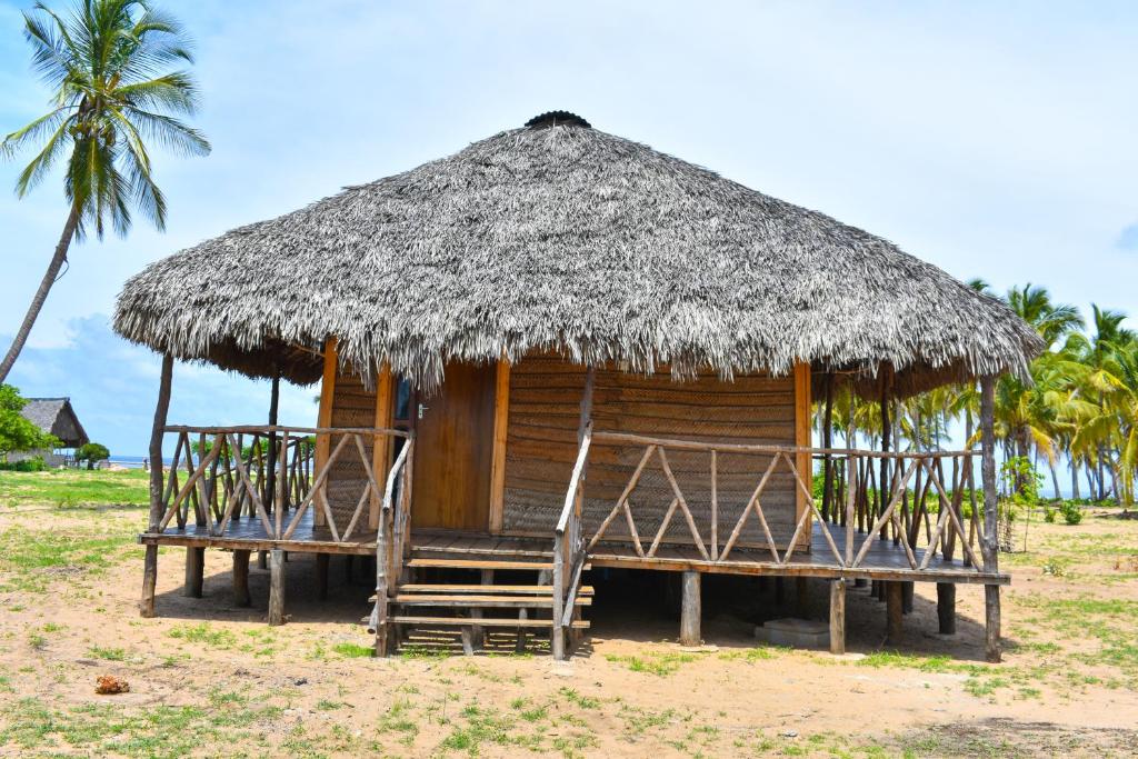 姆特瓦拉Nanano Beach Home Stay的一个带稻草屋顶和长凳的小小屋