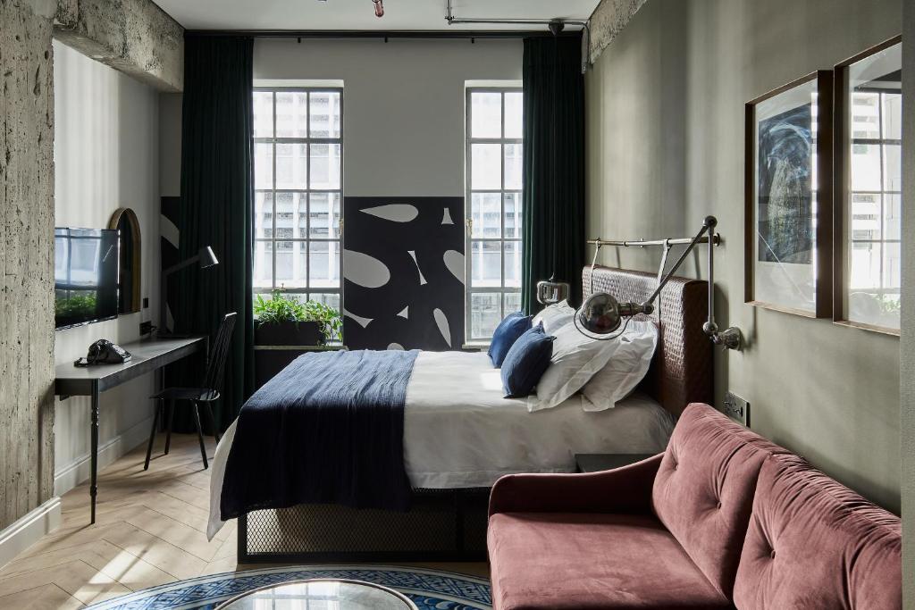 开普敦Gorgeous George by Design Hotels ™的一间卧室配有一张床、一张桌子和一张沙发