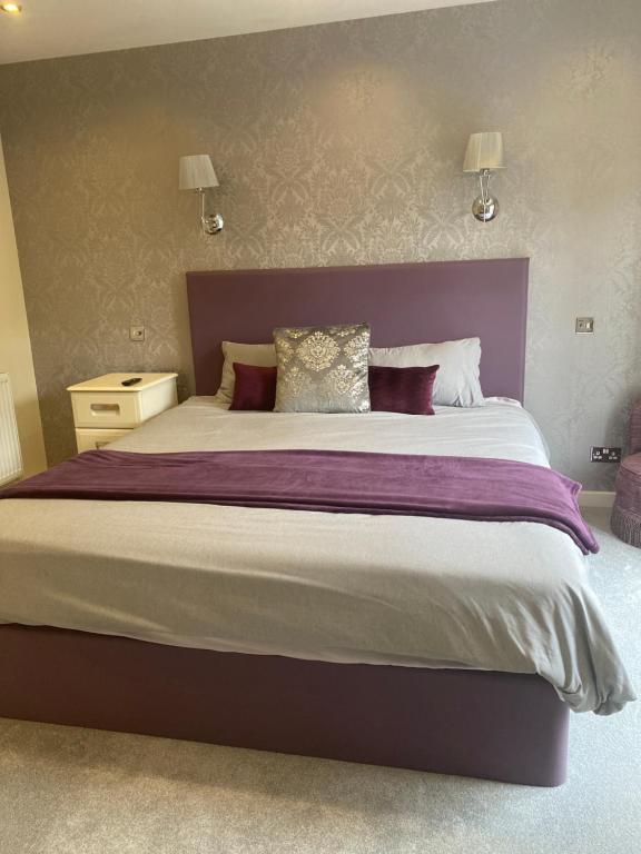 OlneyLamorna的卧室内的一张大床和紫色床头板