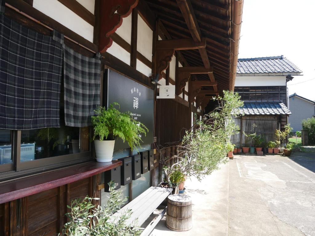 Eiheiji駅前宿舎 禪 shared house zen的一座有门廊的建筑,上面有盆栽植物