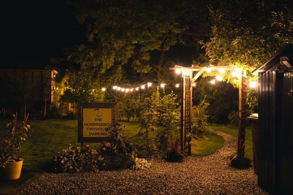 GaradiceThe Horrrsebox Tinyhouse Glamping的夜间花园,有标志和灯