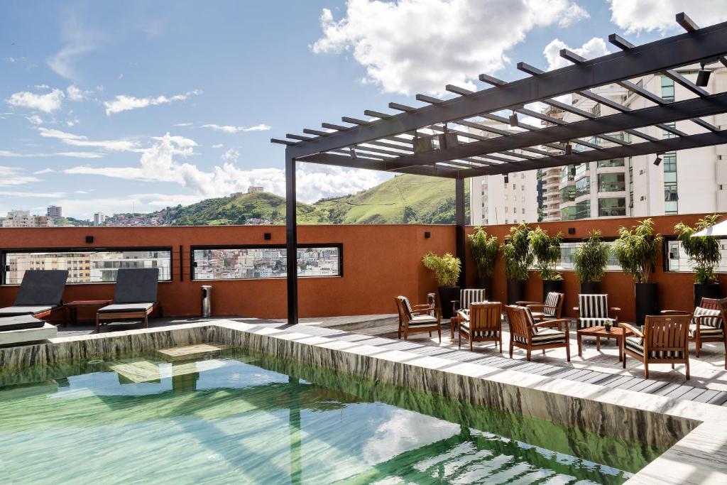 尤西德福拉胜利商务酒店 的一座带桌椅的建筑屋顶上的游泳池
