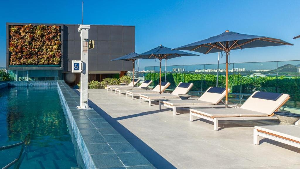 里约热内卢维尼巴拉酒店的游泳池旁的一排躺椅和遮阳伞