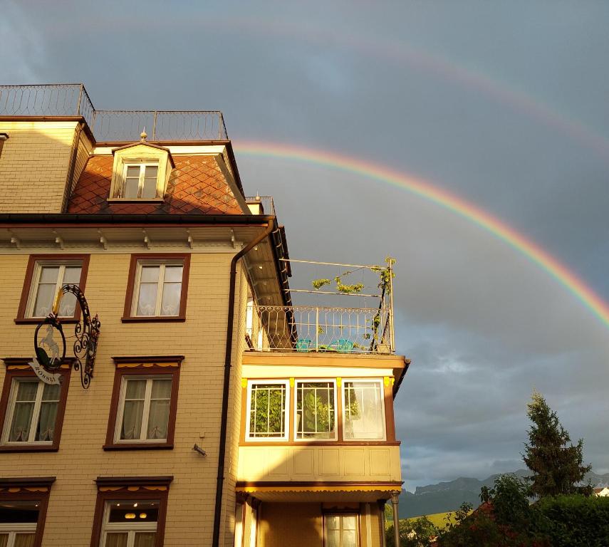 Schwellbrunn罗斯里施维尔布伦住宿加早餐旅馆的房屋上方的天空中的一个彩虹