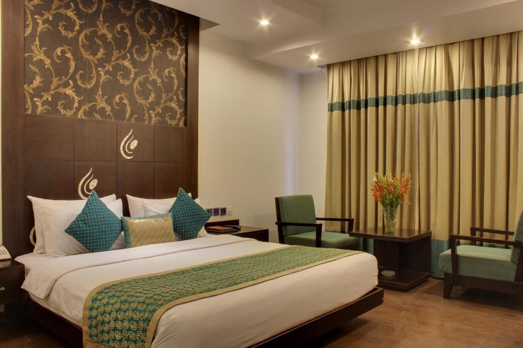 新德里Hotel Godwin Deluxe -Near New Delhi Railway Station - Paharganj的配有一张床和一把椅子的酒店客房