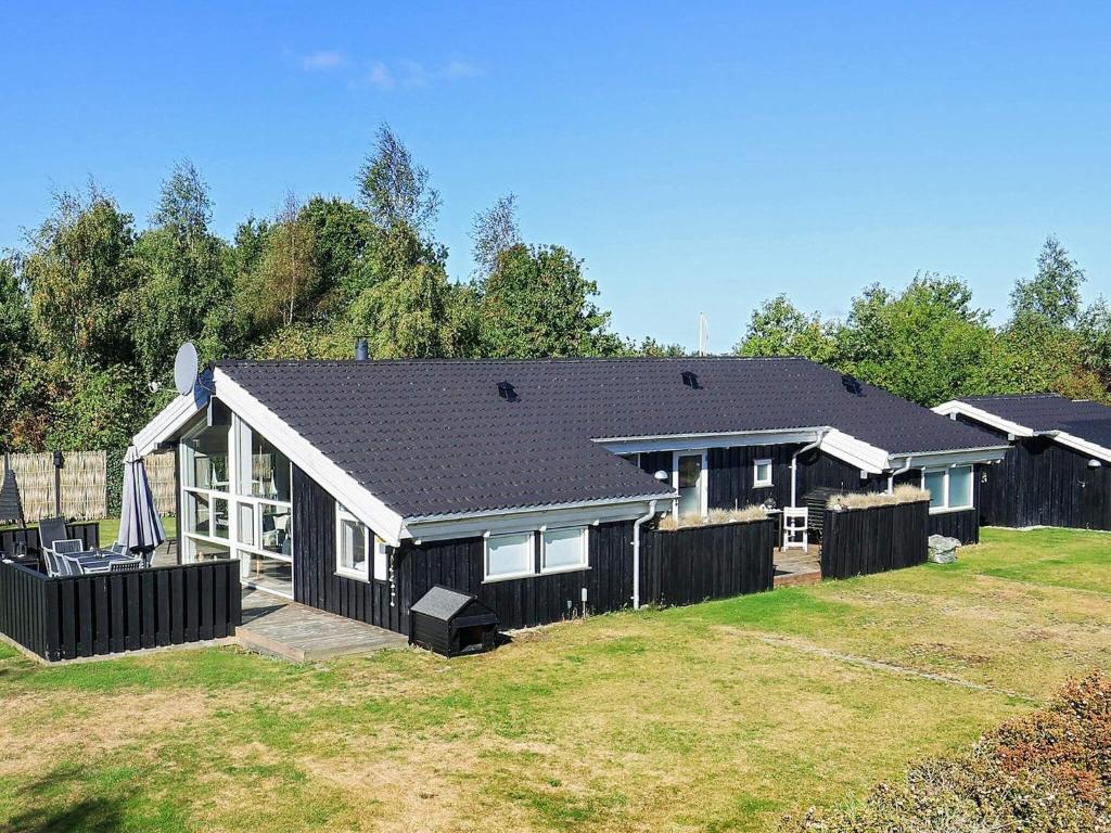 奥特鲁普8 person holiday home in Otterup的院子中带围栏的黑色房子