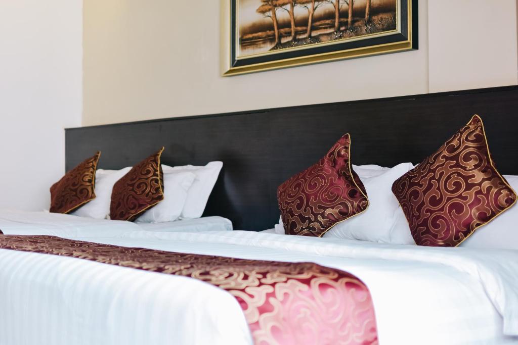 瓜拉丁加奴J套房酒店的两张位于酒店客房的床,配有红色和棕色枕头