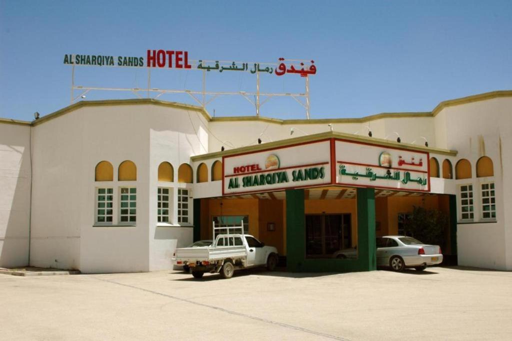 IbrāOYO 142 Al Sharqiya Sands Hotel的前面有停车位的建筑