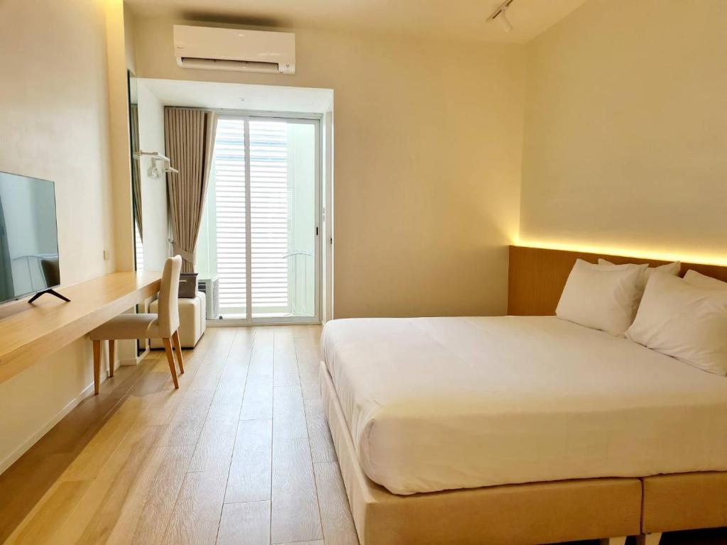 佛丕WIIN Phetchaburi วิน เพชรบุรี的配有一张床、一张书桌和一扇窗户的酒店客房