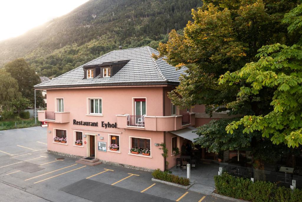 菲斯普Hotel-Restaurant Eyholz的停车场里一座粉红色的大建筑