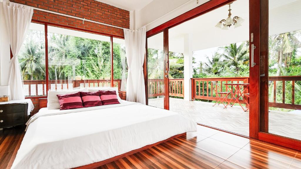 恰洛克拉姆Baan Bhuwann Holiday Apartment的卧室设有白色的床和大窗户
