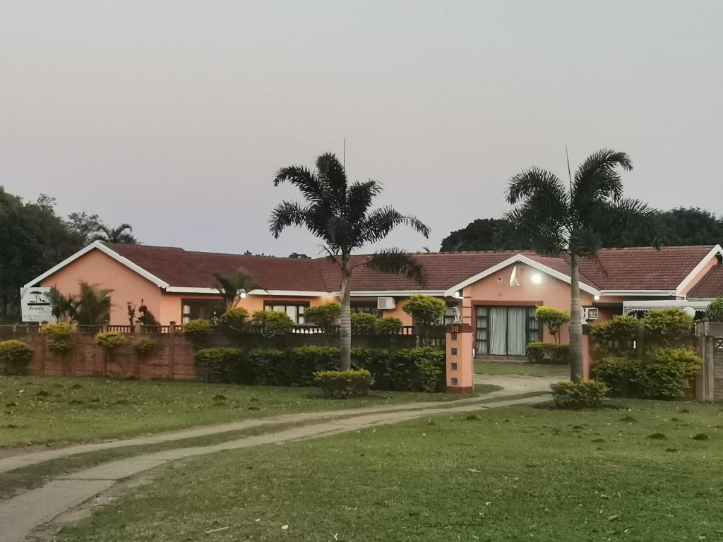 理查兹湾Mavundla guest house的一座粉红色的房子,前面有棕榈树