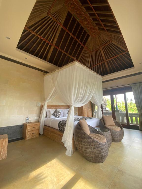乌布Anggarakasih Ubud Villa的一间卧室配有一张带天蓬和椅子的床