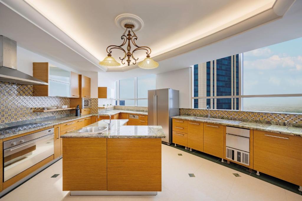 多哈Dusit Hotel & Suites - Doha的大型厨房设有木制橱柜和大窗户