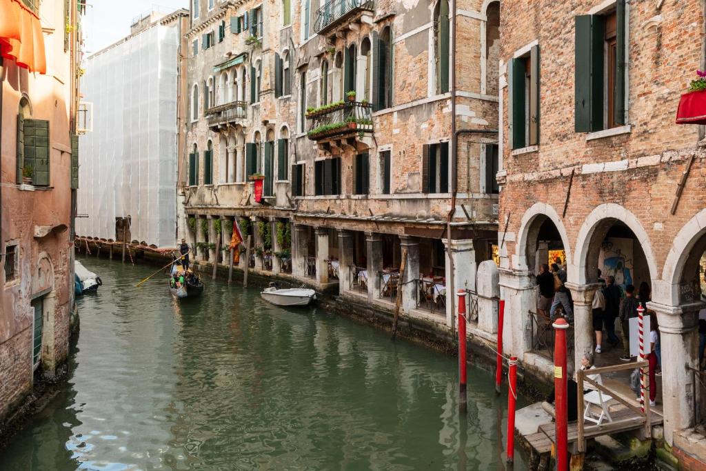 威尼斯Hotel al Sotoportego的两座楼之间一条水中装有船只的运河