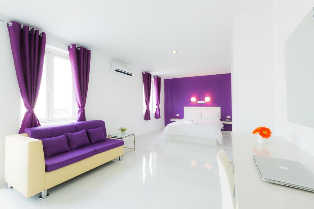 金边金边诚酒店的白色的客房配有紫色的沙发和床。