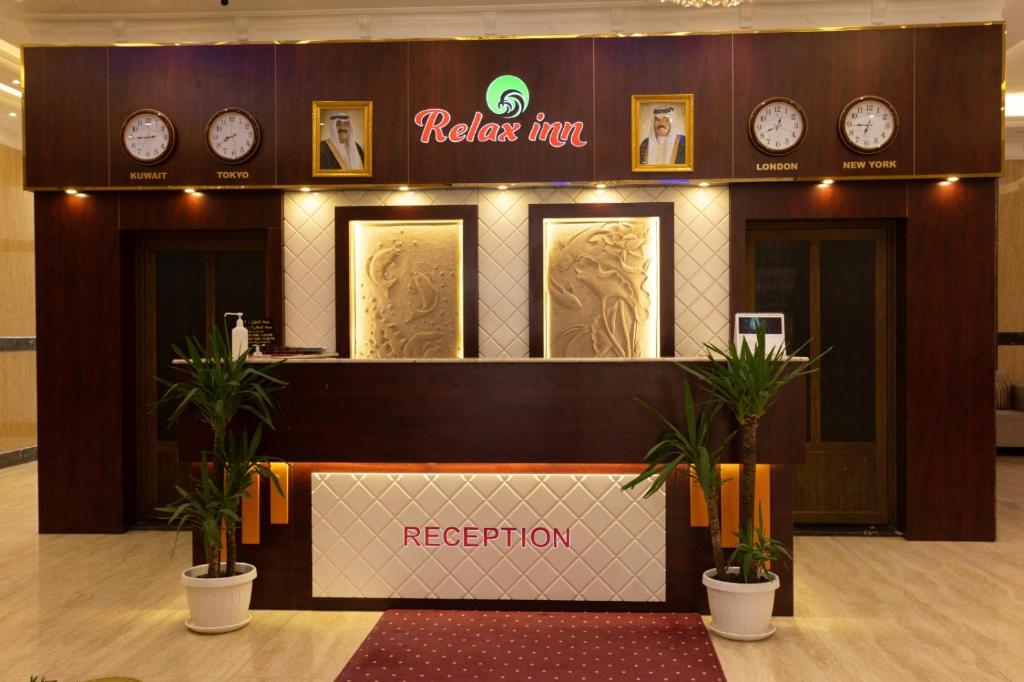 科威特Relax inn Apartment - Fahaheel的酒店大堂设有墙上的时钟和前台
