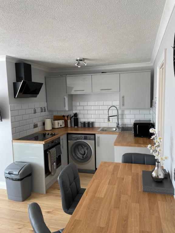 赫姆斯比265 Belle Aire, Modern Property的厨房配有白色橱柜和木桌