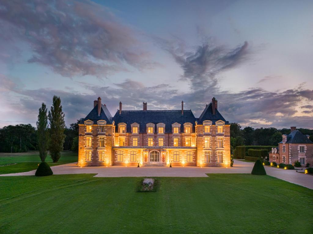 Vernou-en-SologneLa Borde en Sologne Château & Spa的黄昏时分,一座大宅,灯火辉煌