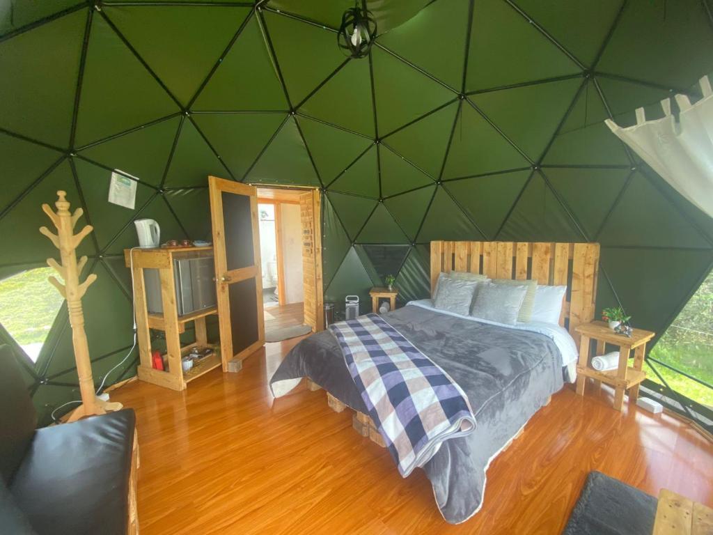 瓜塔维塔Glamping El Refugio的一间卧室设有一张大床和绿色的墙壁