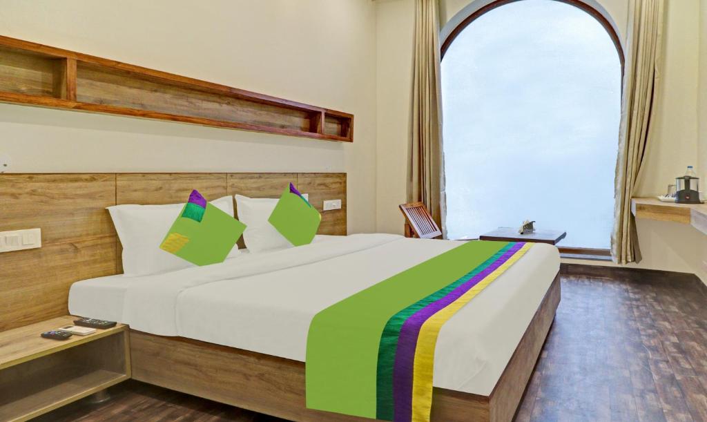 钱德加尔Treebo Trend Delmont的一间卧室配有一张大床和色彩缤纷的毯子