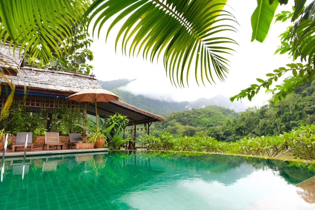 Nongkhiaw曼陀罗欧度假酒店的一座带房子的游泳池,其背景是山脉