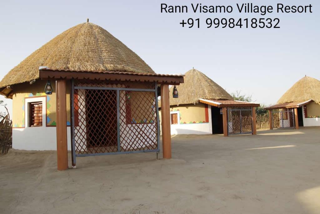 BherandiālaRann Visamo Resort的停车场内一排茅草屋顶的小屋