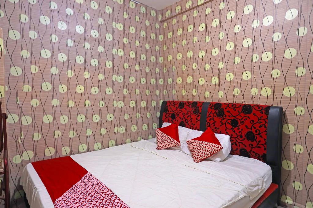 名古屋OYO 91782 Satria Homestay Syariah的一间卧室配有红色和白色枕头的床