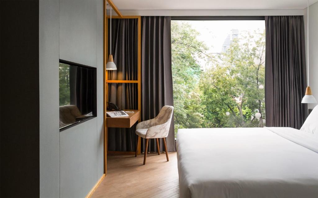 曼谷沃尔沃曼谷酒店的一间卧室配有一张床、一张书桌和一个窗户。
