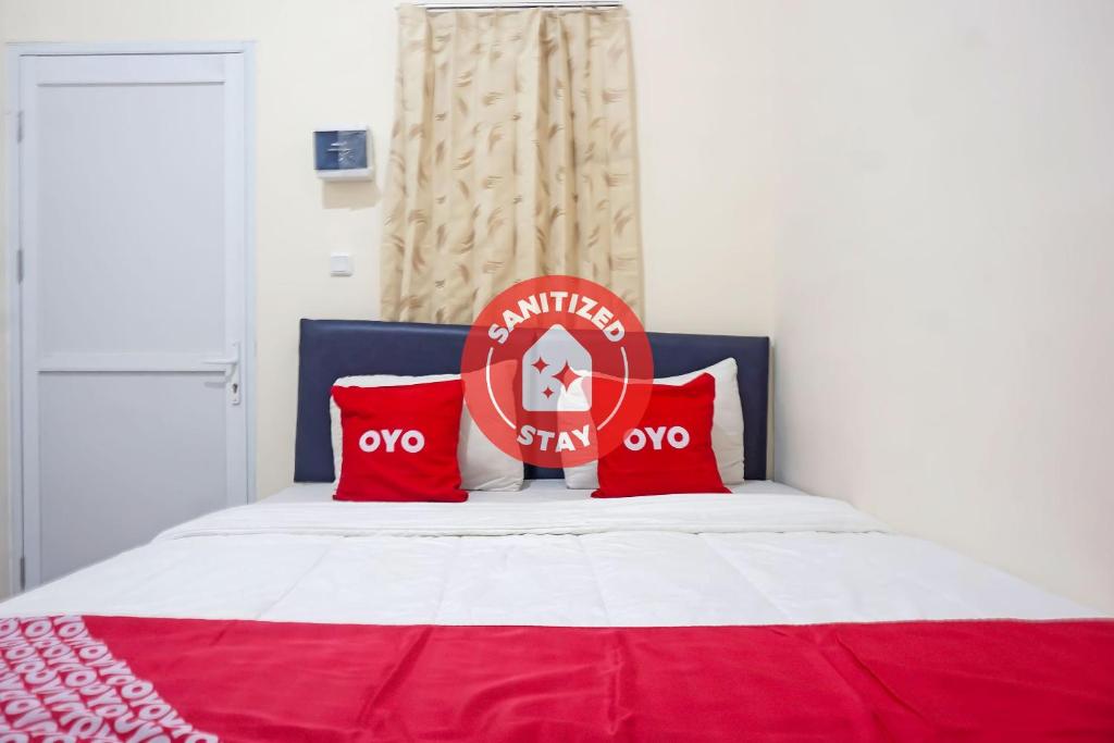 当格浪SUPER OYO Capital O 91790 S1 Residence的红色和白色的床,上面有红色枕头