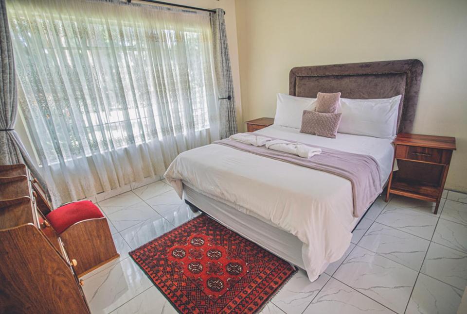 哈拉雷Palm villa的一间卧室设有一张大床和一个窗户。