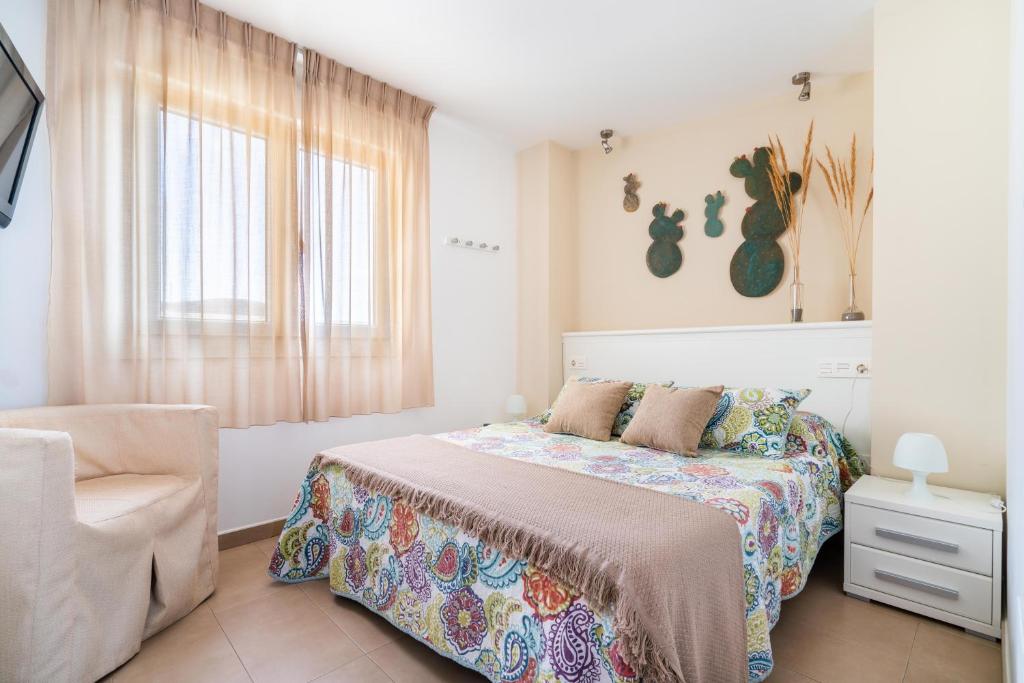 卡沃内拉斯德拉玛尔公寓的卧室配有床、椅子和窗户。