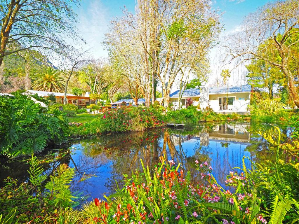 豪特湾Waterland Lodge的花树花园中的池塘