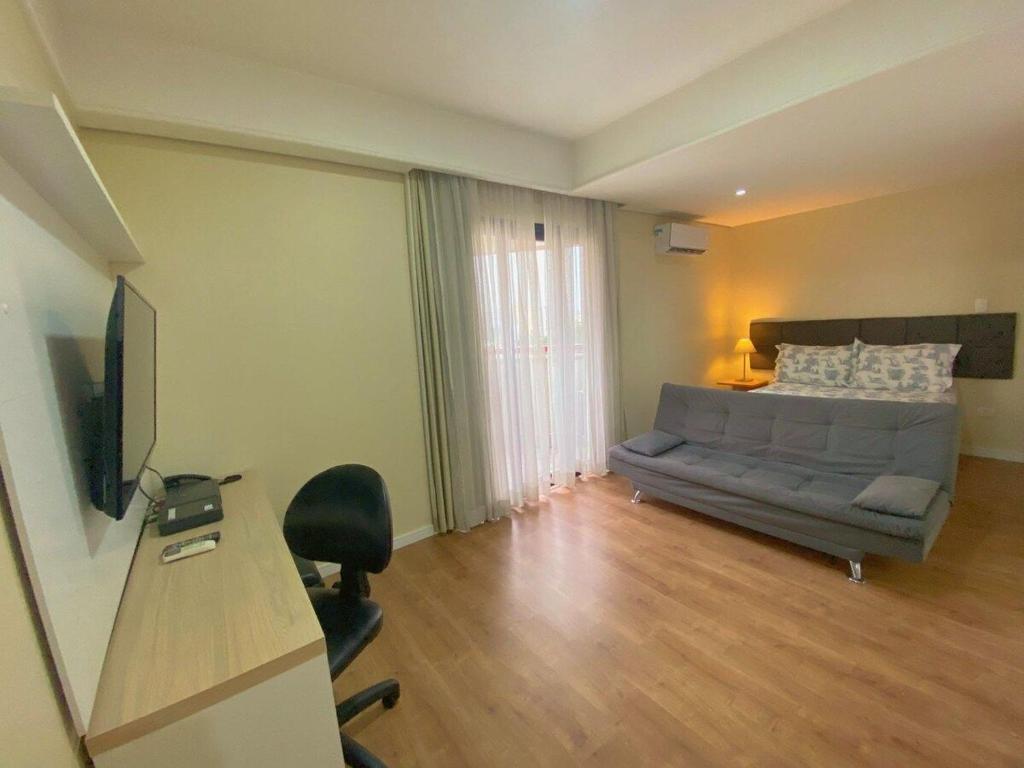圣保罗Flat Bienal Ibirapuera c/ Sacada UH 1107的一间卧室配有一张床、一张书桌和一台电视