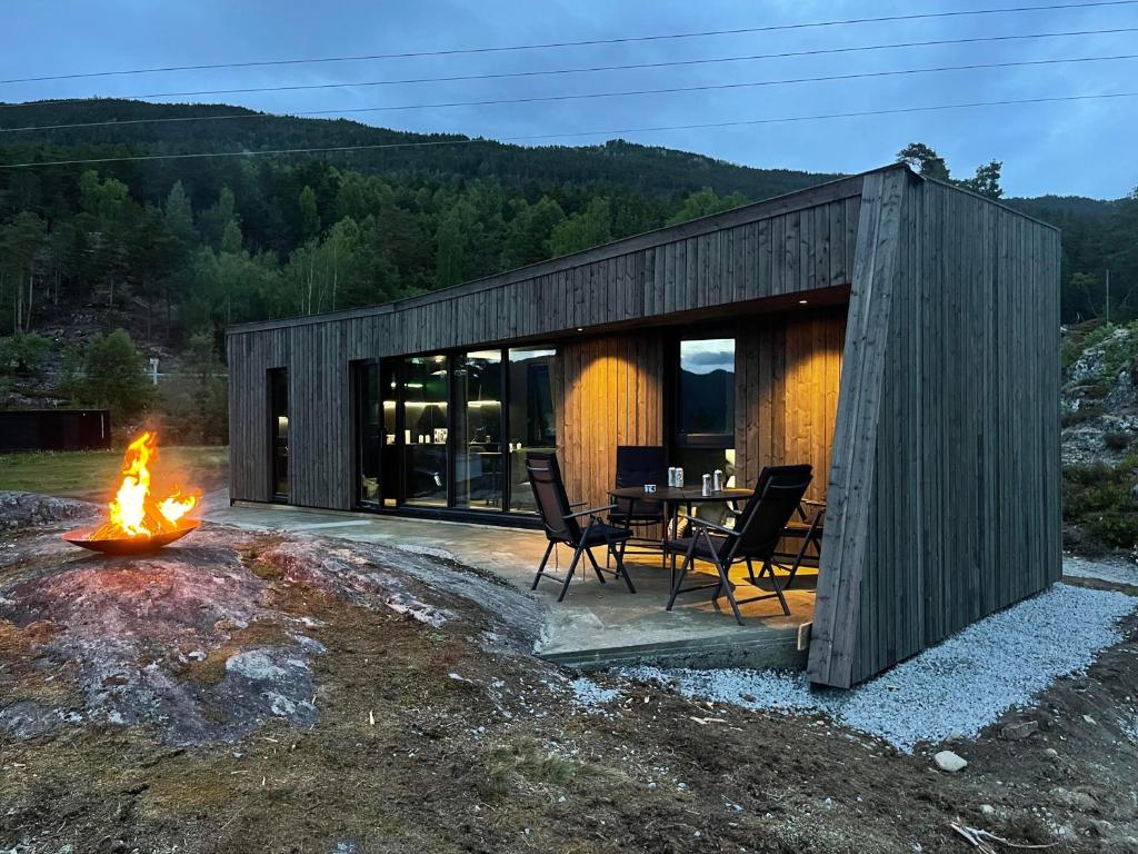 松达尔Sogndal Fjordpanorama的小木屋配有桌椅和壁炉