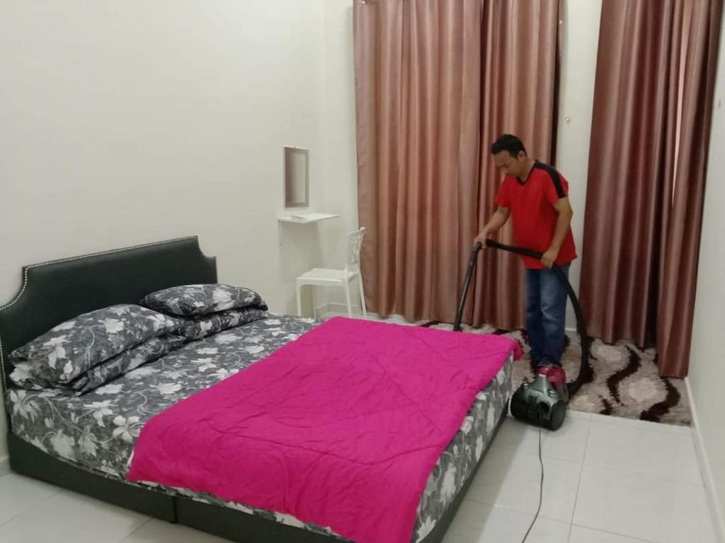 大港Homestay Dorani Sungai Besar的吸尘器清洁卧室,卧室配有床