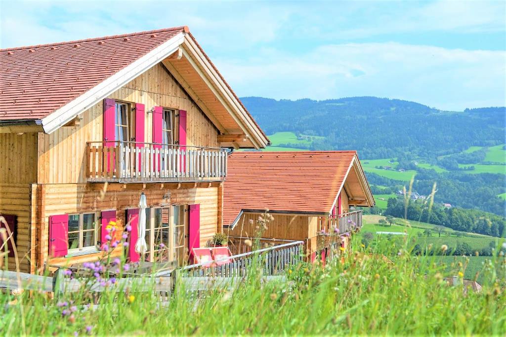 PöllaubergFerienhaus mit Panoramaausblick und Sauna - 3 SZ的木制房屋设有粉红色的窗户和阳台