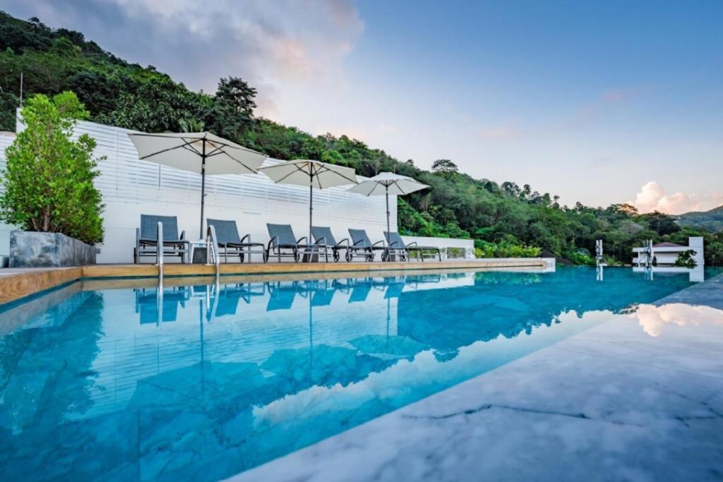 芭东海滩LullaBella Hotel的一个带椅子和遮阳伞的游泳池